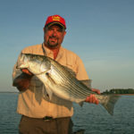 Chip Hamilton with a hefty striper caught early in the morning on lower Lake Hartwell; early morning is prime time during June.