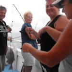Mate Lisa Ashley (right) helps Johanna Seese from Pittsburgh land a trigger fish on the Miss Oregon Inlet. Seese said it was the first fish she ever caught.
